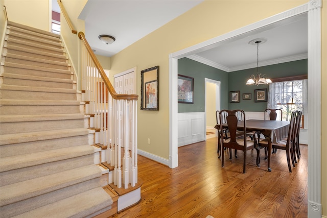 dining space featuring wood-type flooring, ornamental molding, and a notable chandelier