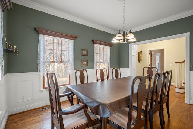 dining room featuring a chandelier, light wood-type flooring, and crown molding