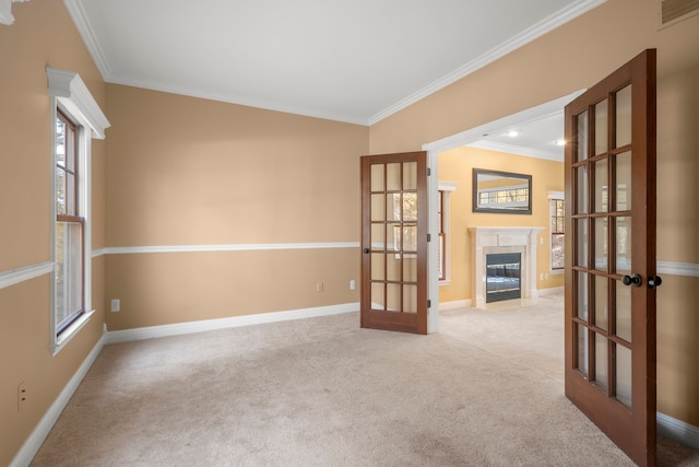 empty room featuring light colored carpet, crown molding, and french doors