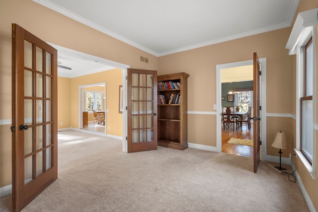 empty room featuring light carpet, french doors, an inviting chandelier, and crown molding