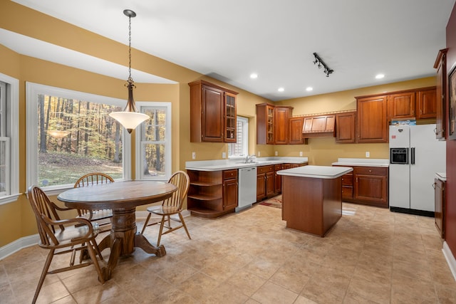 kitchen with pendant lighting, a kitchen island, white appliances, and a healthy amount of sunlight