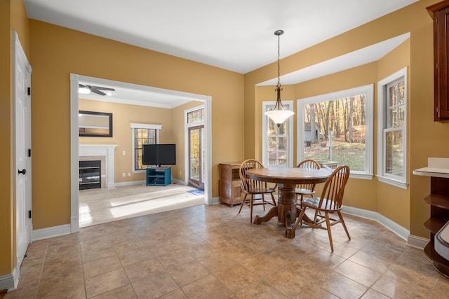 tiled dining area with ceiling fan and crown molding