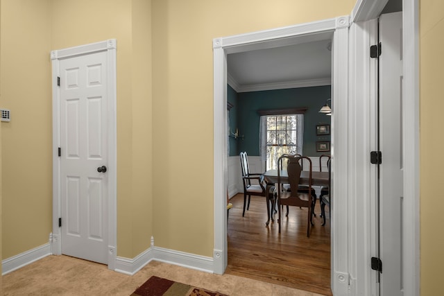 hallway with light hardwood / wood-style floors and crown molding