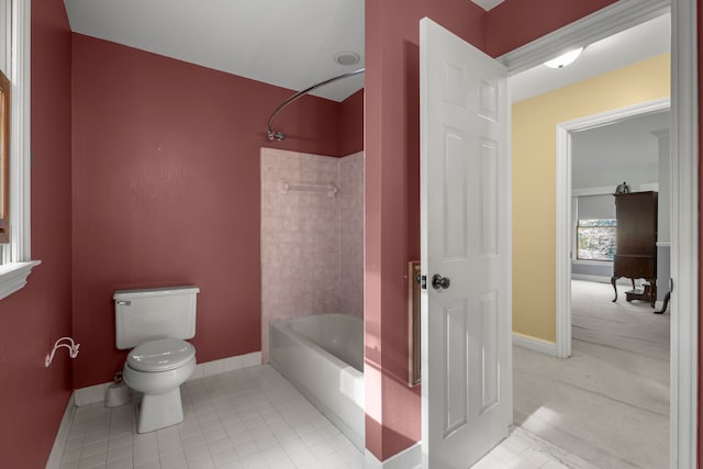 bathroom with tile patterned flooring, tiled shower / bath combo, and toilet