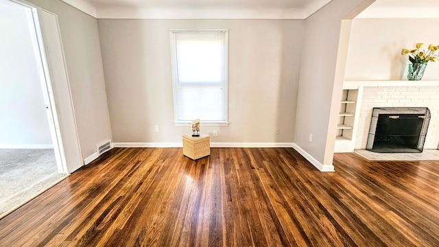 unfurnished living room with dark hardwood / wood-style floors, built in features, and a fireplace