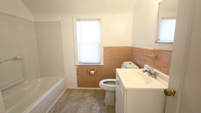 bathroom featuring toilet, tile walls, vanity, vaulted ceiling, and a tub