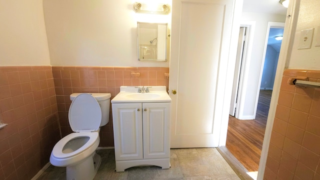 bathroom featuring tile walls, toilet, and vanity