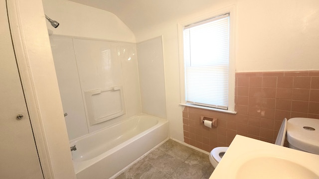 full bathroom with plenty of natural light, tile walls, toilet, and vaulted ceiling