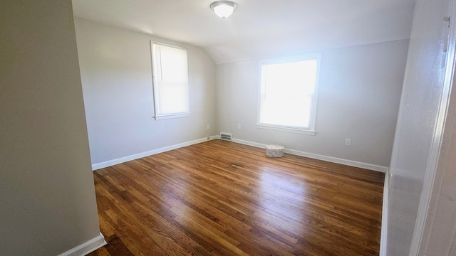 additional living space with vaulted ceiling and dark hardwood / wood-style flooring