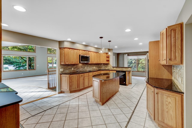 kitchen featuring pendant lighting, dark stone countertops, kitchen peninsula, and a wealth of natural light