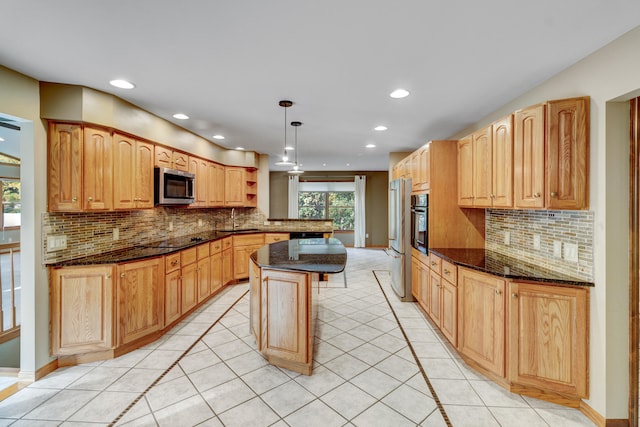 kitchen featuring a center island, dark stone counters, decorative backsplash, appliances with stainless steel finishes, and decorative light fixtures