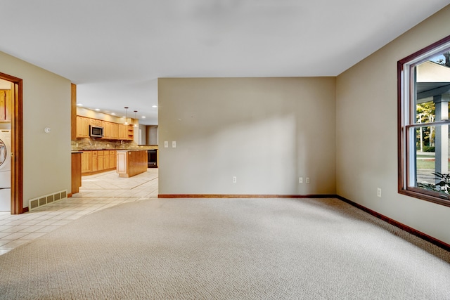 unfurnished living room with light tile patterned flooring and washer / clothes dryer