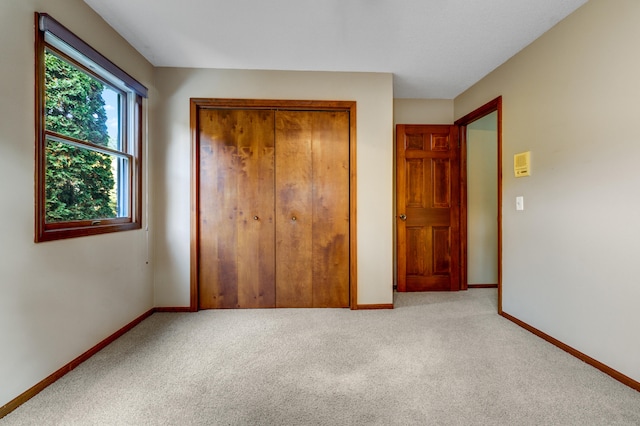 unfurnished bedroom featuring light colored carpet and a closet