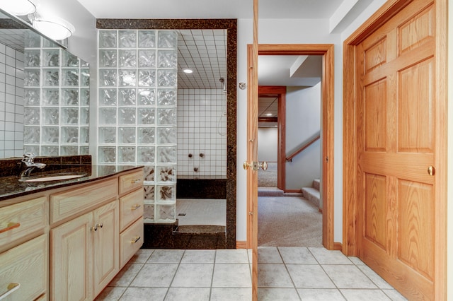 bathroom with tile patterned flooring, vanity, and tiled shower