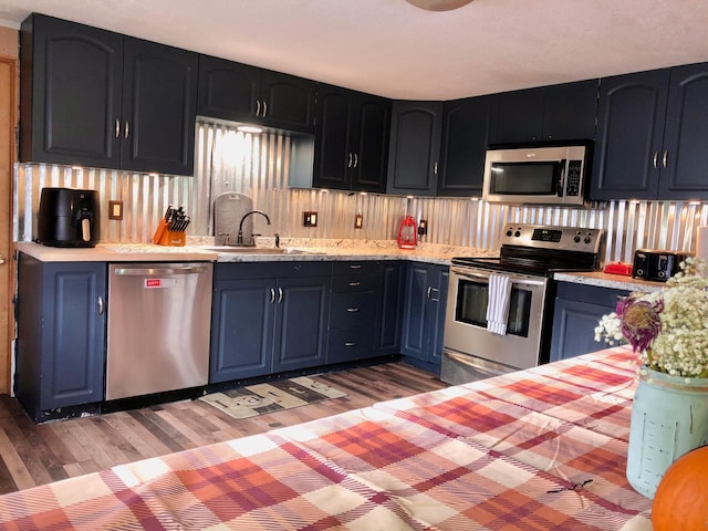 kitchen featuring blue cabinetry, stainless steel appliances, dark wood-type flooring, and sink