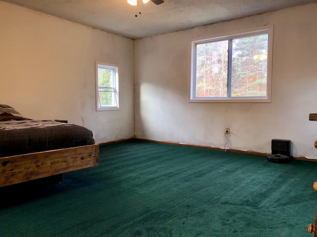 carpeted bedroom featuring a textured ceiling, multiple windows, and ceiling fan