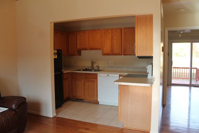 kitchen with stove, black fridge, white dishwasher, sink, and light hardwood / wood-style flooring