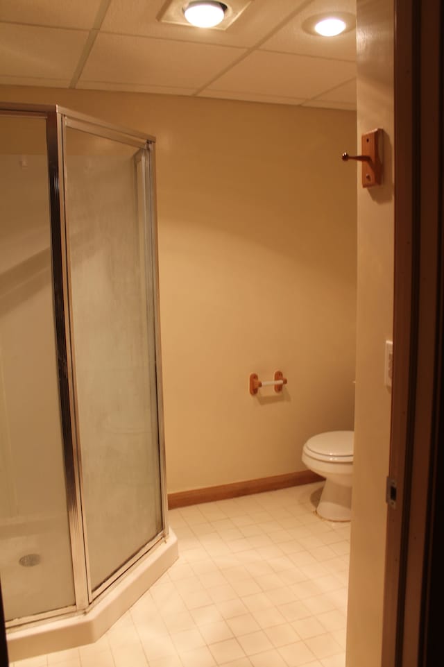 bathroom with a paneled ceiling, toilet, and walk in shower