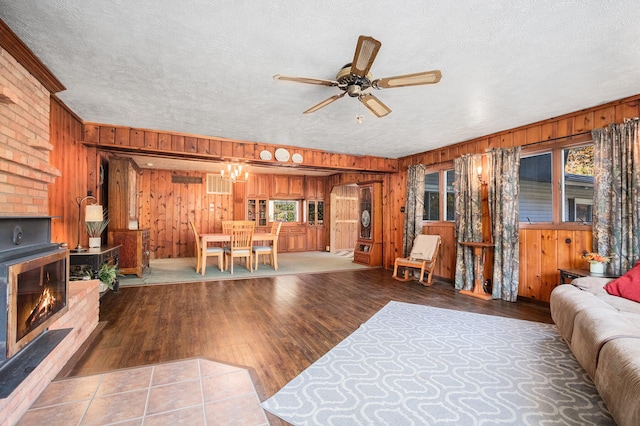 living room with a fireplace, hardwood / wood-style floors, ceiling fan, and wooden walls