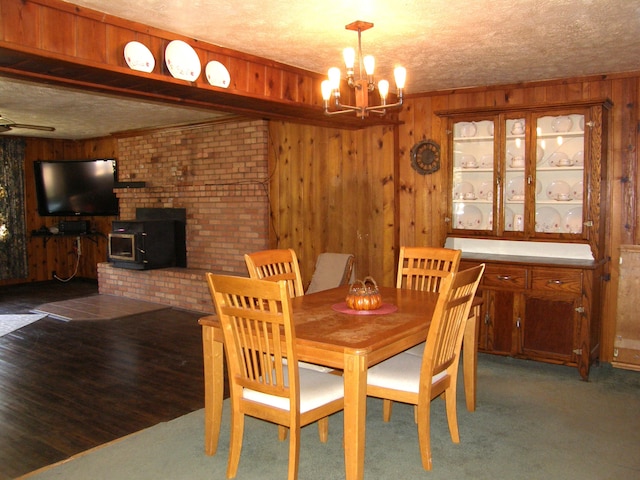 carpeted dining area featuring brick wall, a wood stove, wooden walls, and a notable chandelier