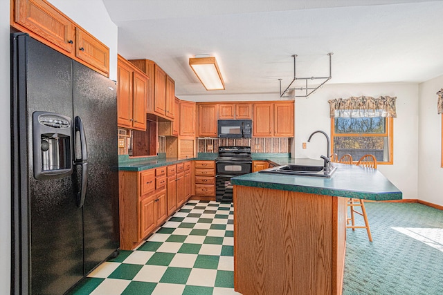 kitchen with black appliances, sink, a kitchen bar, and an island with sink