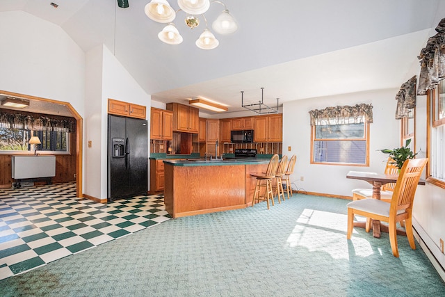 kitchen with lofted ceiling, black appliances, a kitchen breakfast bar, baseboard heating, and kitchen peninsula