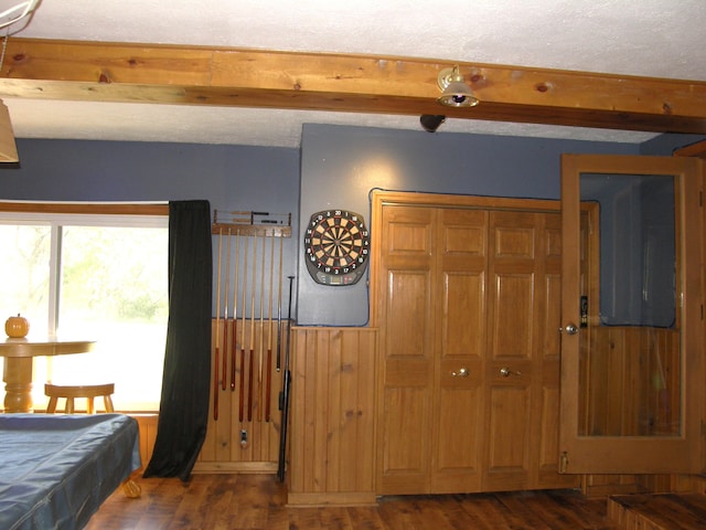 bedroom featuring wooden walls, beamed ceiling, dark hardwood / wood-style floors, a closet, and pool table