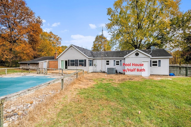 back of property featuring a covered pool, a yard, and central air condition unit