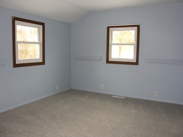 carpeted empty room featuring lofted ceiling