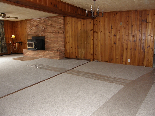 unfurnished living room featuring beamed ceiling, a wood stove, a textured ceiling, and wooden walls