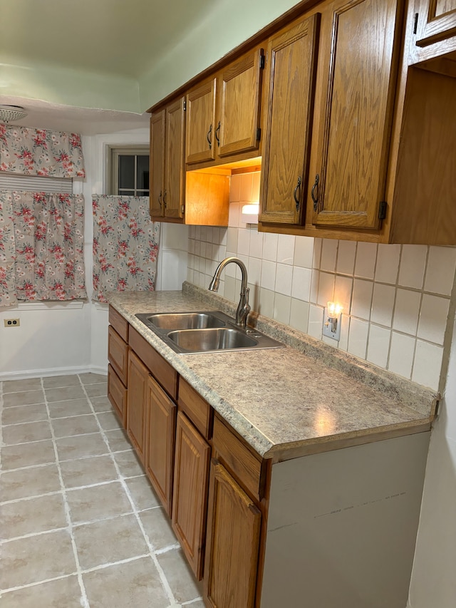 kitchen with decorative backsplash, light tile patterned floors, and sink