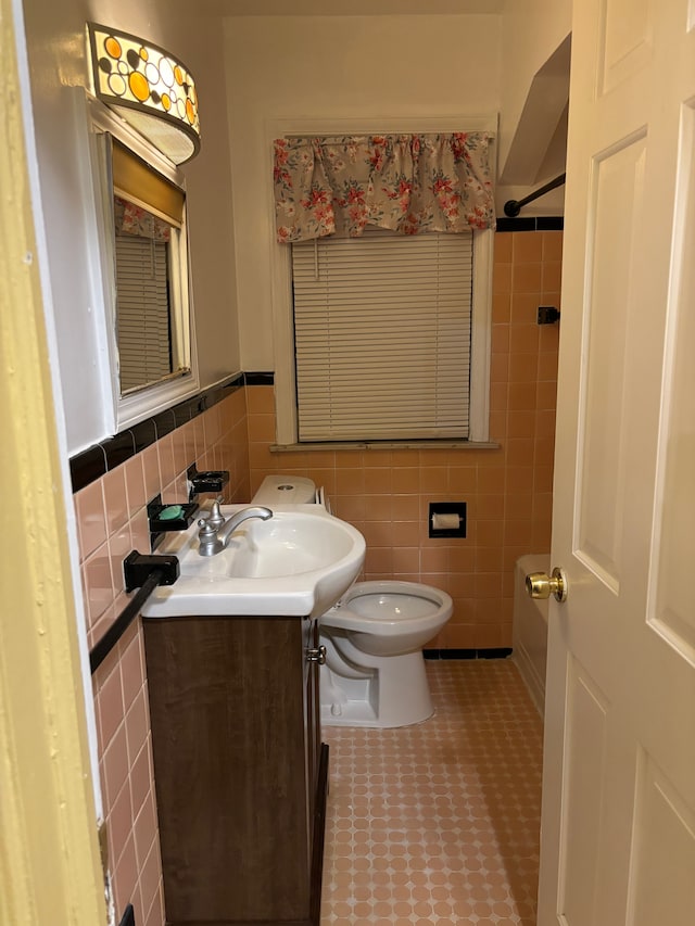 bathroom featuring vanity, toilet, and tile walls