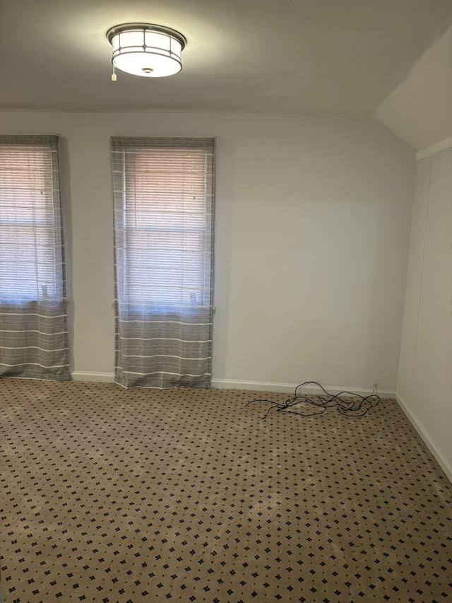 carpeted spare room with vaulted ceiling and a wealth of natural light