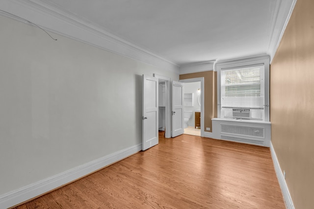 unfurnished bedroom with connected bathroom, crown molding, radiator heating unit, and light wood-type flooring