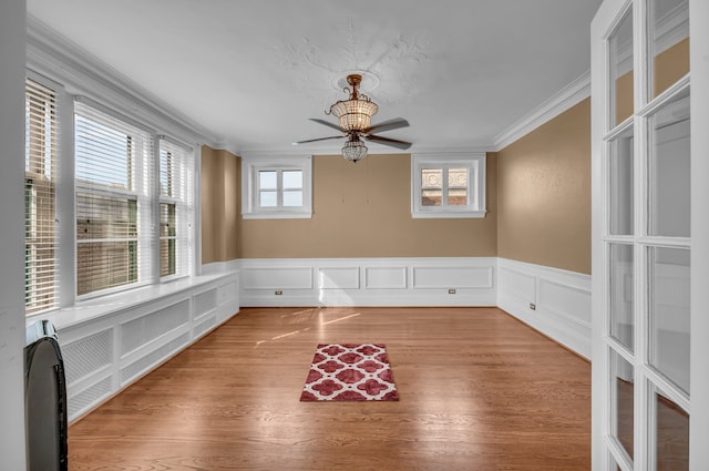 empty room featuring hardwood / wood-style flooring, ceiling fan, a healthy amount of sunlight, and crown molding