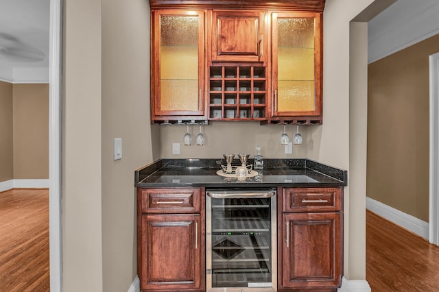 bar featuring hardwood / wood-style flooring, wine cooler, and dark stone counters