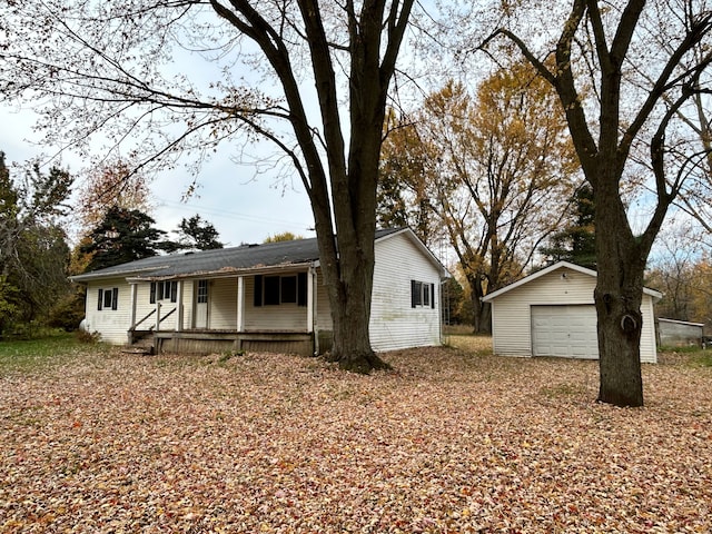 ranch-style home with covered porch, a garage, and an outbuilding