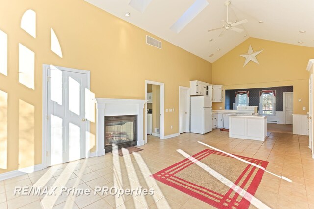 10300 Lange Rd, Birch Run, MI 48415 - unfurnished living room featuring high vaulted ceiling, a glass covered fireplace, light tile patterned floors, and a ceiling fan