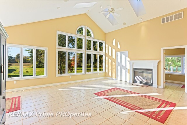 10300 Lange Rd, Birch Run, MI 48415 - unfurnished living room featuring a skylight, light tile patterned floors, high vaulted ceiling, a ceiling fan, and a glass covered fireplace