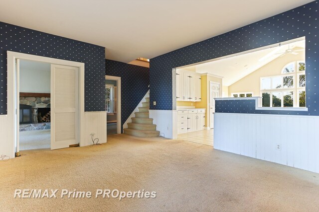 10300 Lange Rd, Birch Run, MI 48415 - unfurnished living room with carpet flooring, a wainscoted wall, wallpapered walls, a stone fireplace, and stairs