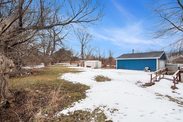 yard layered in snow with a garage and an outdoor structure