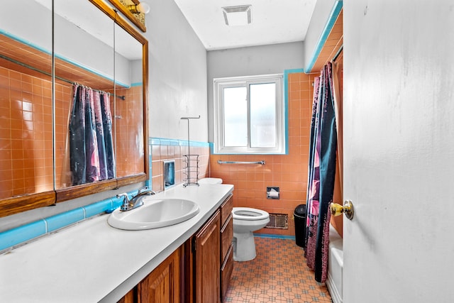 full bathroom with vanity, toilet, tile walls, and shower / tub combo