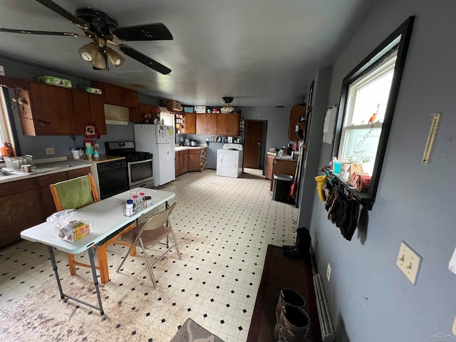 kitchen featuring white refrigerator, ceiling fan, black dishwasher, washer / clothes dryer, and stainless steel range with gas stovetop