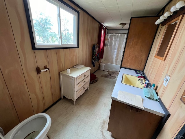 bathroom featuring shower / bath combination with curtain, sink, and wooden walls