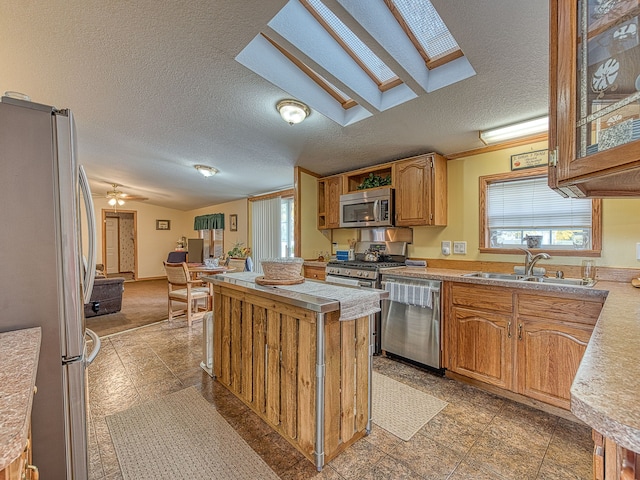 kitchen featuring lofted ceiling, sink, ceiling fan, a textured ceiling, and appliances with stainless steel finishes