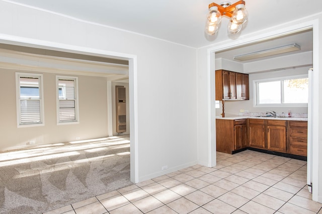 kitchen with light tile patterned floors, sink, an inviting chandelier, white refrigerator, and ornamental molding