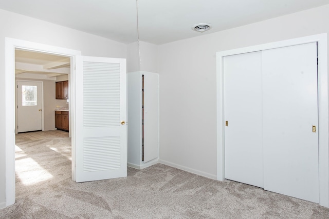 unfurnished bedroom featuring light carpet and a closet