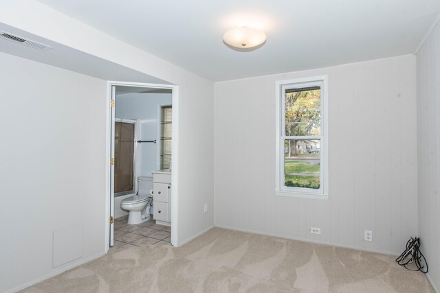 unfurnished bedroom featuring light carpet and connected bathroom