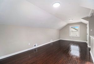 bonus room with dark wood-type flooring and vaulted ceiling