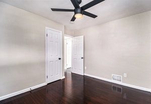 empty room with ceiling fan and dark hardwood / wood-style flooring